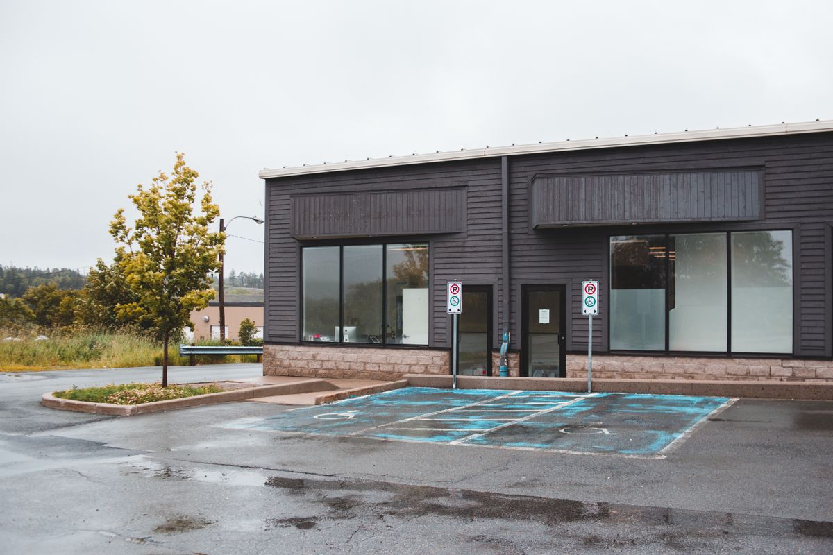 Commercial building entrance beside wet marked parking spaces.